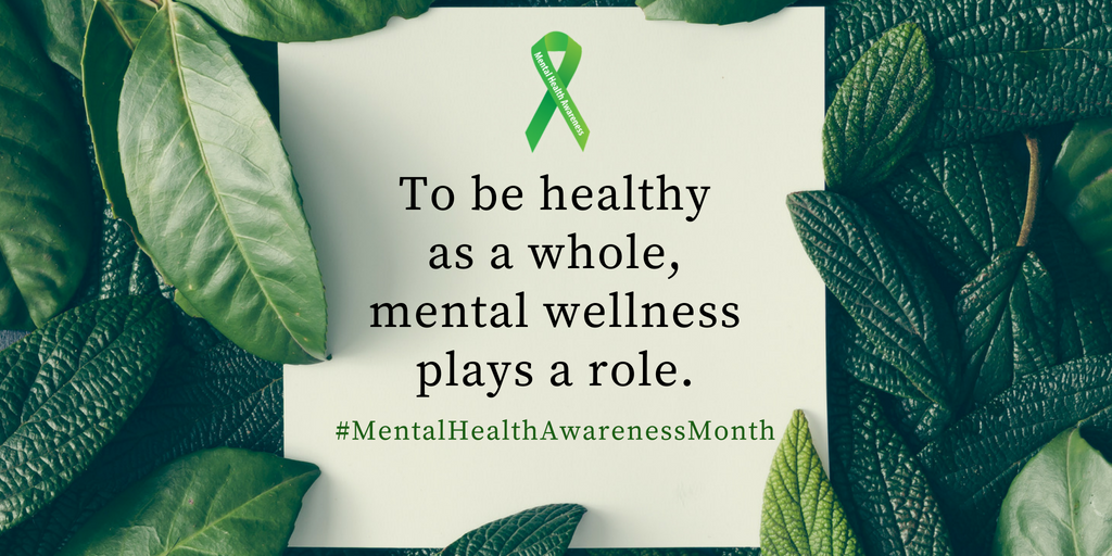 A card featuring a green mental health awareness ribbon and the text "To be healthy as a whole, mental wellness plays a role. #MentalHealthAwarenessMonth" laid over a background of lush green leaves.