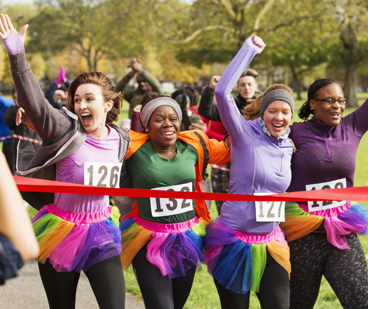 Cheerful women crossing a race finish line in vibrant tutus.